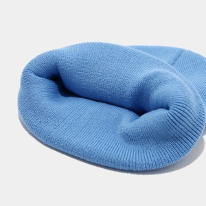 Gros plan du bonnet en maille bleu ciel montrant la texture douce et les coutures
