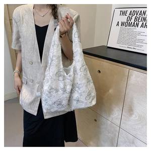 Detailed view of an oversized white tote bag with intricate butterfly embroidery