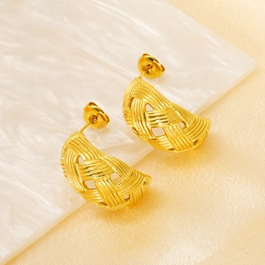 Detail of 18K gold-plated titanium steel earrings with woven mesh texture on marble