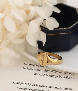 Detail of a polished 18k gold-plated signet ring with an engraved rose design