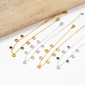 Detail of shell charms and colorful zircon pendants on gold and silver anklet sets