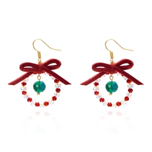 Close-up of Christmas wreath earrings with red beads and a delicate silk bow