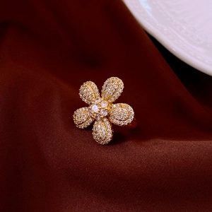 Macro shot of gold vintage flower ring with sparkling zircon petals on brown satin
