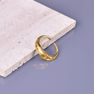 Irregular gold adjustable ring with wavy organic texture on a neutral stone surface