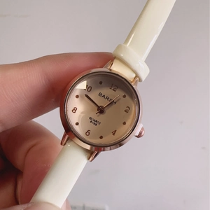 Detailed close-up of champagne dial with rose gold case and white leather strap