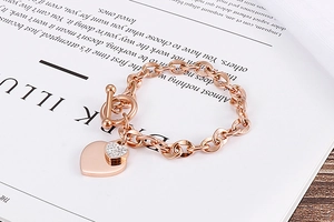 Detail of rose gold OT buckle bracelet with double heart charms on a magazine background