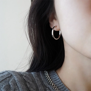 Close-up of polished silver hoop earrings on model with a minimalist knit sweater