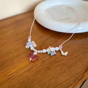 Close-up of sweet resin butterfly necklace with imitation pearls on wooden surface