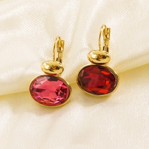 Elegant gold drop earrings featuring oval-cut red gemstones on soft silk fabric background