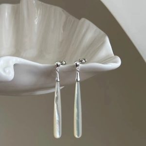 Elegant teardrop shell earrings with silver metal beads displayed on a white shell holder