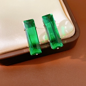 Macro detail of emerald green rectangular zirconia earrings in silver four-prong setting
