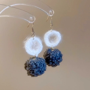 Dettaglio di anelli all'uncinetto bianchi e pompon blu scuro su ganci dorati per l'inverno