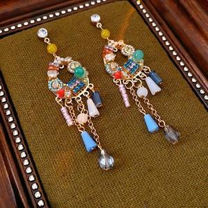 Détail macro de boucles d'oreilles bohèmes à pompons colorés et perles sur velours