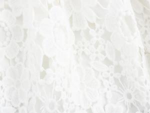 Gros plan sur la dentelle florale blanche délicate et le tissage complexe de cette robe