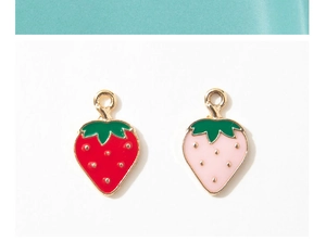 Detail of red and pink strawberry alloy charms with golden hanging loops on white background