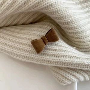 Gros plan sur une pince à cheveux nœud en velours marron sur maille blanche