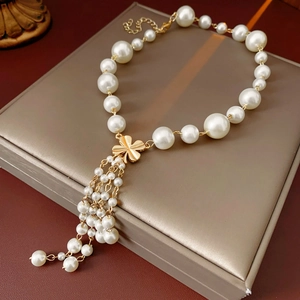 Detail of gold flower pendant with pearl tassels on a minimalist sweater necklace