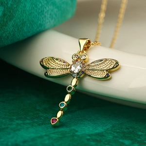 Exquisite gold dragonfly pendant necklace with colorful zircons on a textured background