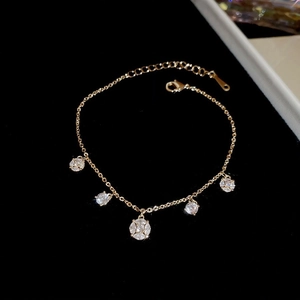 Detailed close-up of gold-plated bracelet featuring zircon floral charms on black velvet