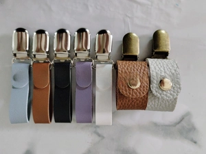 Detailansicht der Leder-Hut-Clips in sieben Farben auf weißem Marmorhintergrund