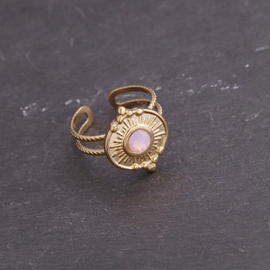 Détail d'une bague dorée vintage avec zircon rose et anneau tressé texturé
