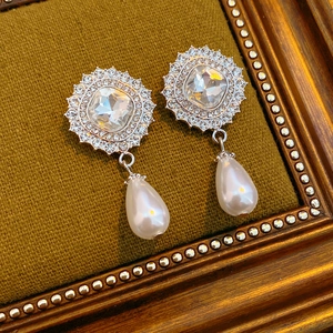 Detailed shot of silver drop earrings with square gemstone and dangling teardrop pearl