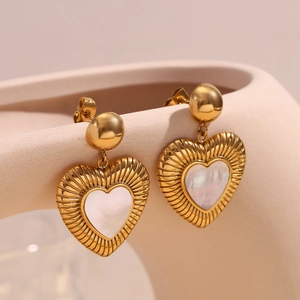 Détail de boucles d'oreilles cœur plaquées or 18K avec nacre blanche incrustée