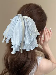 Detail of light blue mesh bow hair claw clip with satin ribbons and pearl on wavy hair