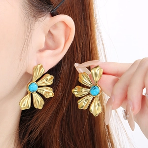 Close-up of vintage gold flower stud earrings with turquoise gemstone on a model