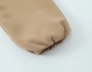 Gros plan du poignet élastique sur veste kaki montrant la texture du coton sergé dense