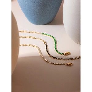Detailed view of 18k gold plated tennis bracelets with emerald green, black and white stones