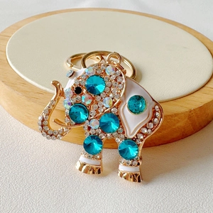 Detail of cute golden elephant keychain with sparkling blue crystals and white enamel finish