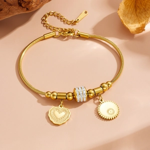 Bracelet chaîne serpent en acier doré avec pendentif cœur et perles cristal sur socle bois