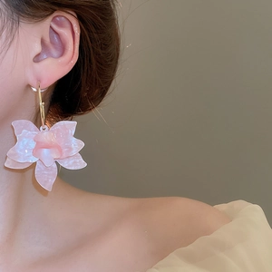 Gros plan de boucles d'oreilles fleurs en résine rose montrant les détails des pétales