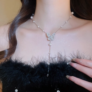 Dettaglio di un'elegante collana a farfalla in argento con perle indossata da modella