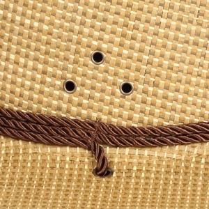 Detail of woven straw texture with decorative rope and metallic eyelets on sun hat