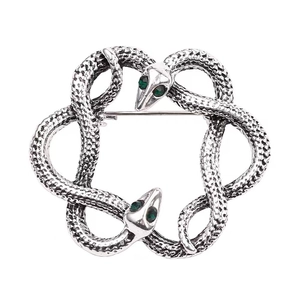 Detailed view of intertwined vintage snakes brooch with silver scales and green zircon eyes