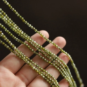 Close-up of olive green faceted zircon beads on a titanium steel clavicle necklace