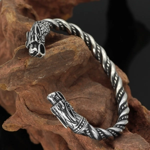 Details des silbernen Wikinger-Drachenarmbands auf einem rustikalen Holzblock