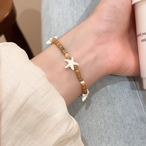 Detail of bohemian starfish charm bracelet with brown striped beads on a wrist
