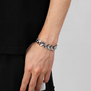 Close-up of a men's silver stainless steel Cuban link bracelet worn on a wrist