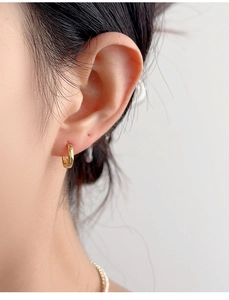 Close-up of minimalist gold sterling silver hoop earring worn on the earlobe