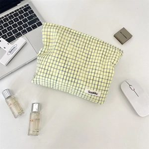 Macro detail of yellow checkered makeup bag on a clean desk with office accessories