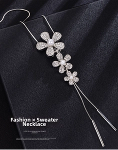 Macro shot of silver flower sweater chain with white pearls and rhinestones on black silk