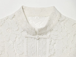 Detail view of white lace blouse featuring an elegant mandarin collar and frog closure