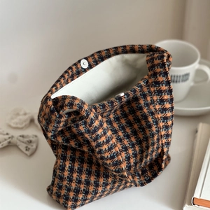 Close-up of the orange houndstooth tweed handbag showing magnetic clasp and inner lining