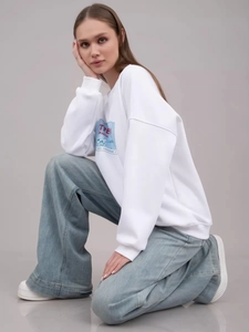 Detailaufnahme von weißem Baumwoll-Sweatshirt mit blauem Aufdruck und weiter Jeans