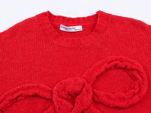 Detailed view of red chunky knit sweater featuring a prominent 3D knitted bow on the chest