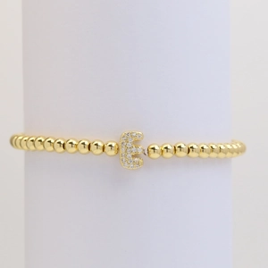 Detailed macro view of gold-plated bead bracelet with cubic zirconia letter E charm