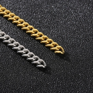 Macro shot of gold and silver cuban link chains on a black textured leather background